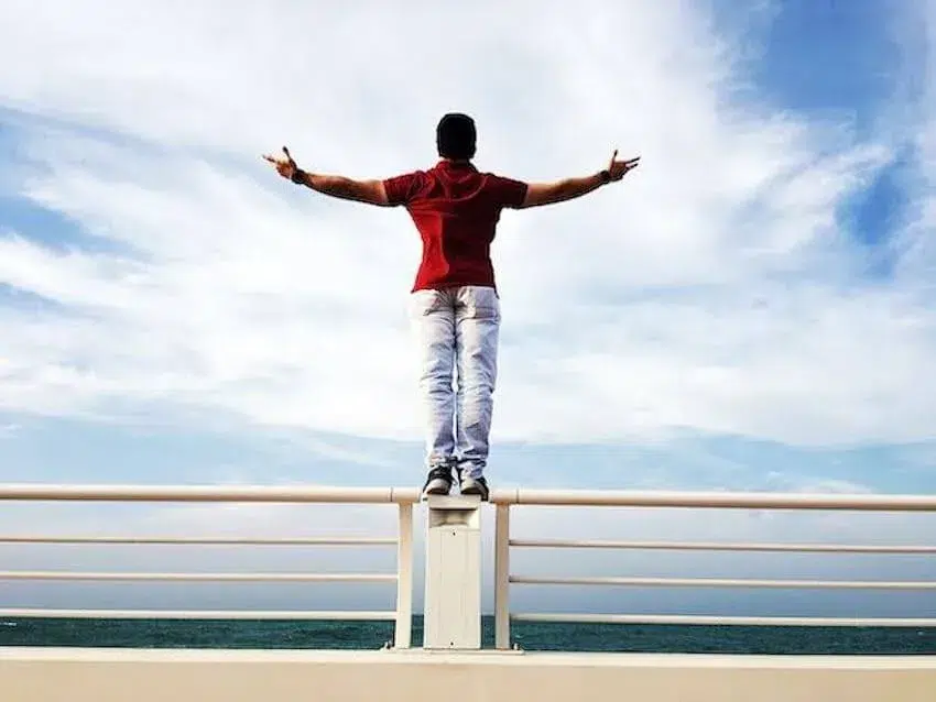 man in red shirt standing up while his arms out