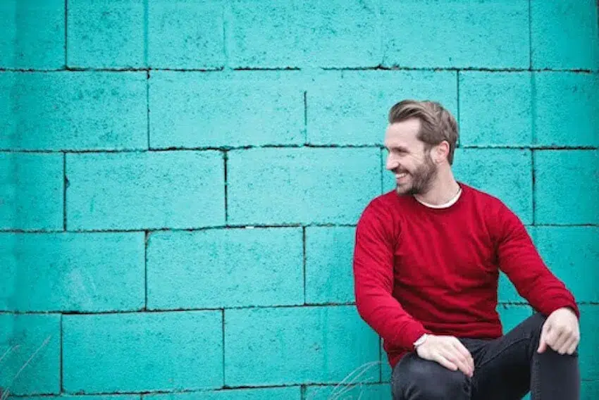 man smiling in front of a blue wall