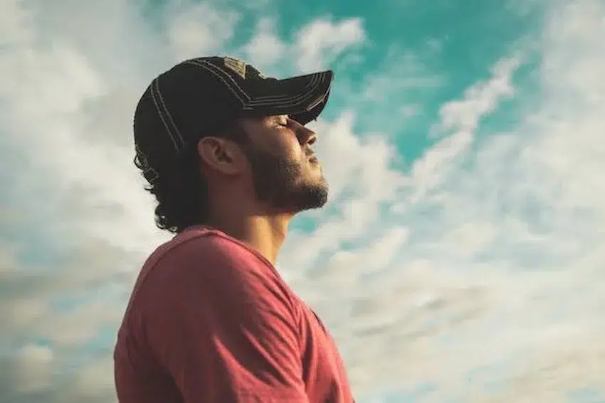 man wearing a cap facing the sky with his eyes closed