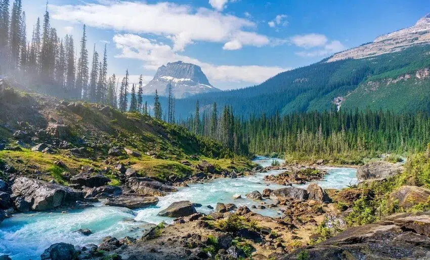 a scenic image of a river running through a forest within a mountain range