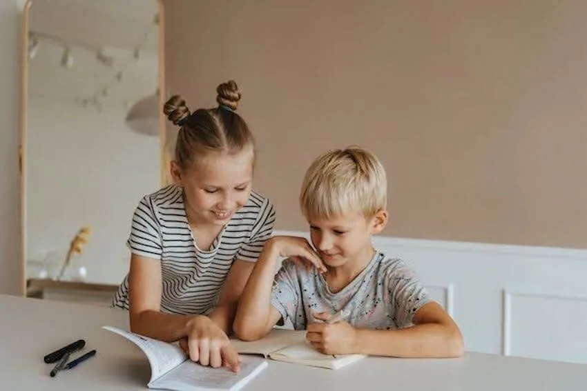 a girl reading to a younger boy