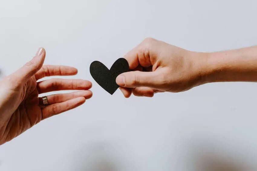 a person handing a paper heart cutout to another person