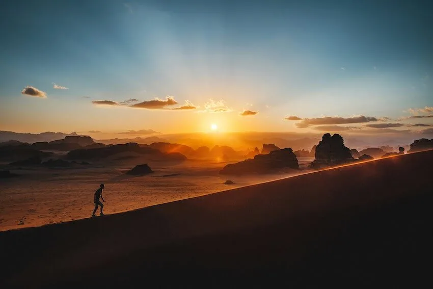 person walking up a path at sunset