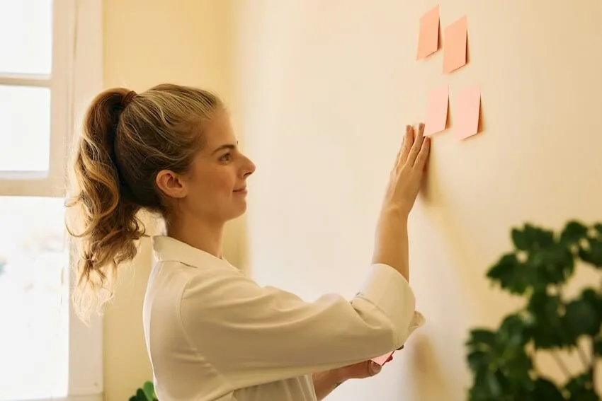 woman putting up sticky notes on her wall