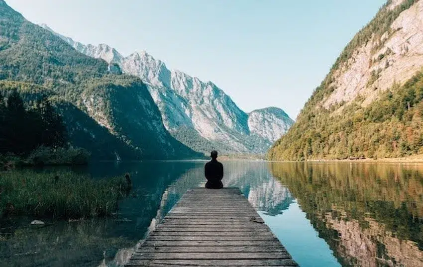 Man sitting at the end of a pier enjoying the beautiful scenery