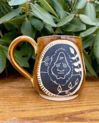 a mug with a cartoon drawing of Big Foot from the company PrettyUglyArtworks on Etsy