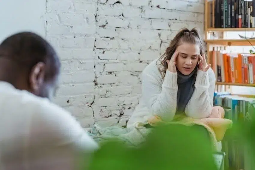 woman with her hands on her temples while speaking to her therapist