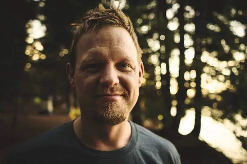 smiling man in the woods looking at the camera