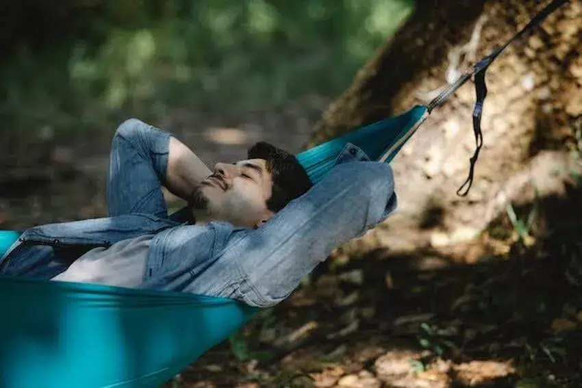 smiling man laying in a blue hammock