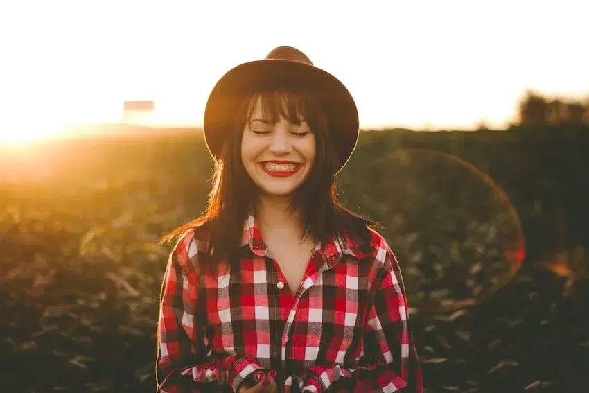 smiling woman in a red checkered shirt and hat