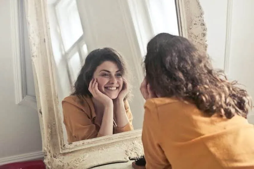 smiling woman looking at herself in a mirror
