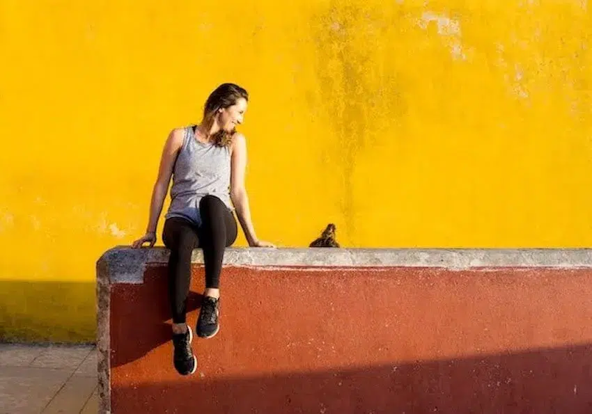 smiling woman sitting on a ledge looking down