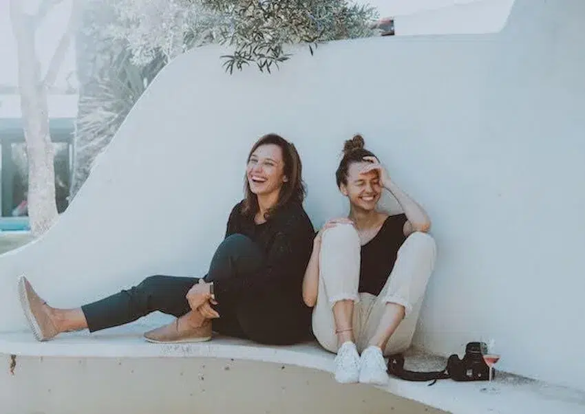 two women sitting on the ground, laughing