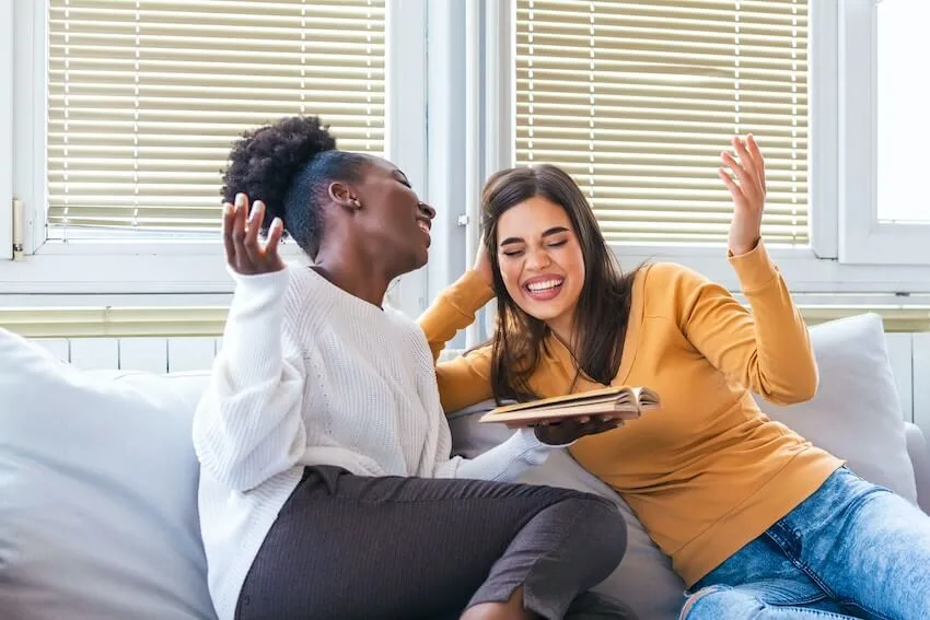 two friends laughing over a photo album