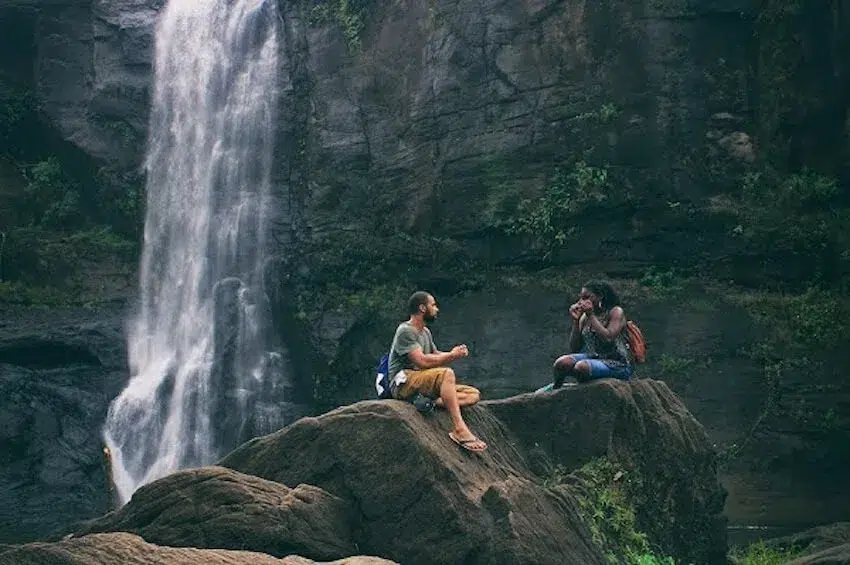 two friends sitting by a waterfall
