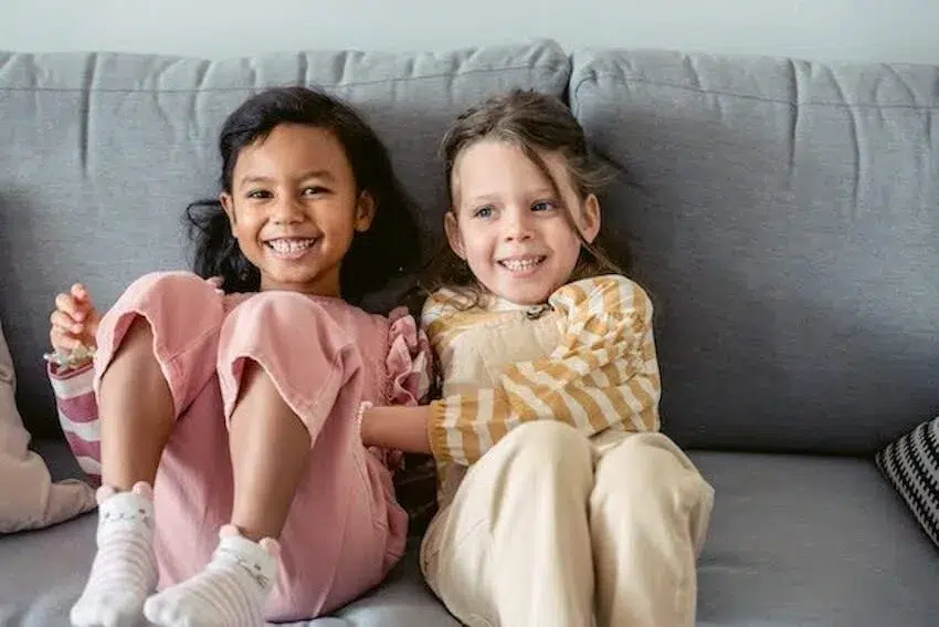 two girls laughing while sitting on a couch