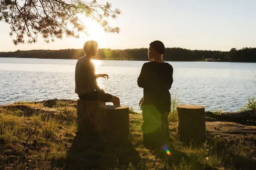 two men talking outside by a river