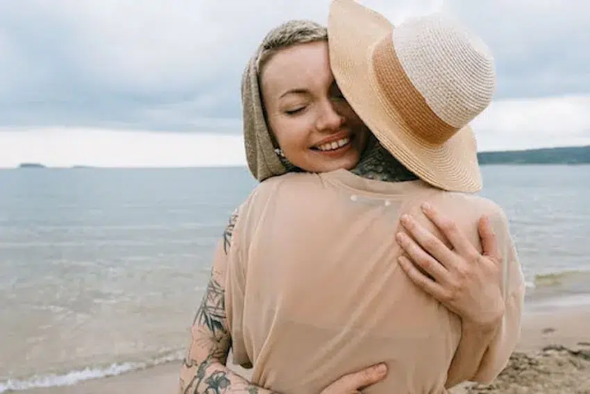 two women hugging on a beach
