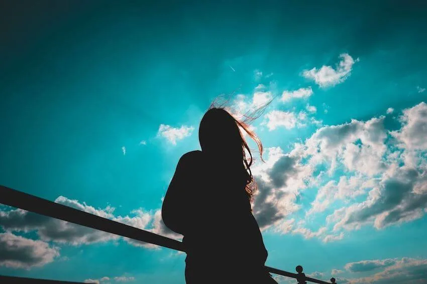 woman standing against a railing looking up at the sky