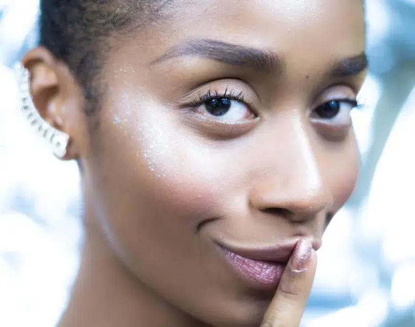 woman looking at the camera with her right pointer finger against her lips telling you to keep a secret