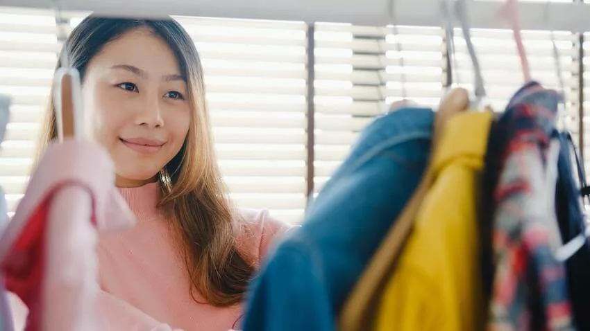 smiling woman looking through her jackets in her closet