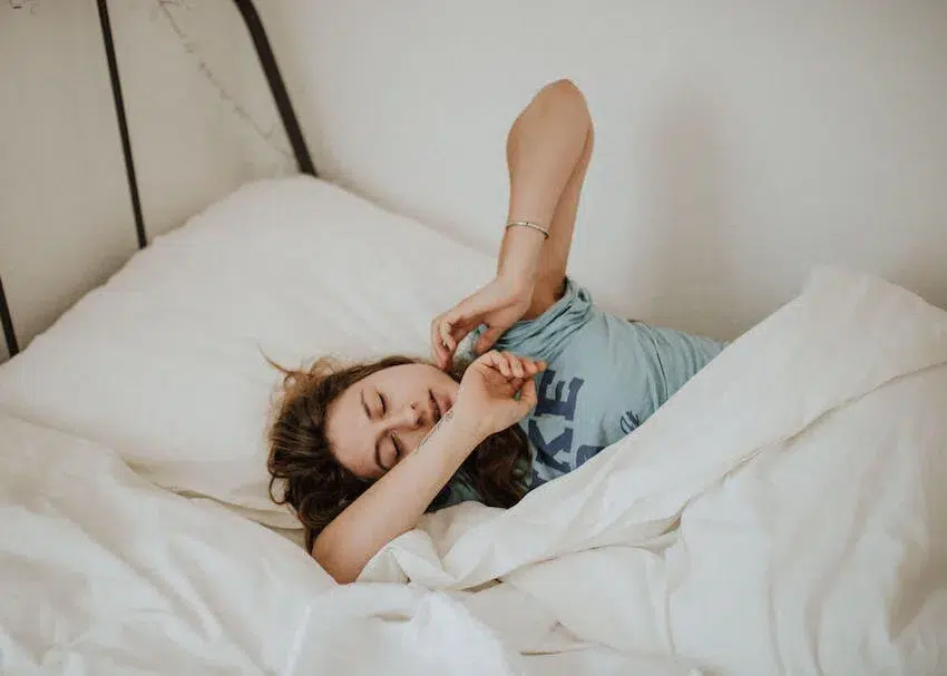 a woman asleep in bed in a funny position