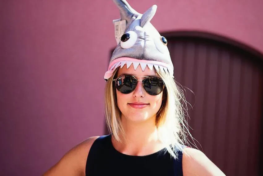 woman in sunglasses wearing a funny hat in the shape of a shark on her head