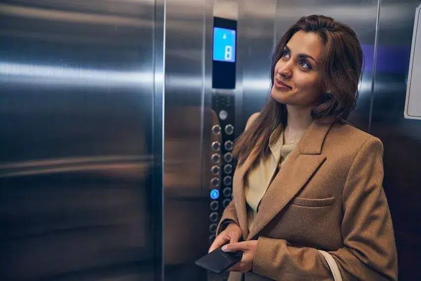 woman standing in an elevator with an amused look on her face