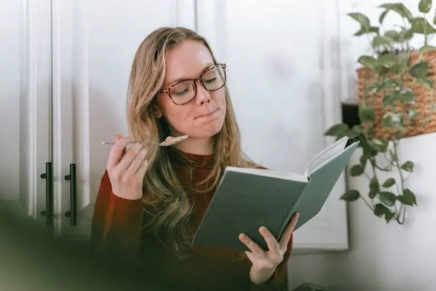 woman eating and reading a book