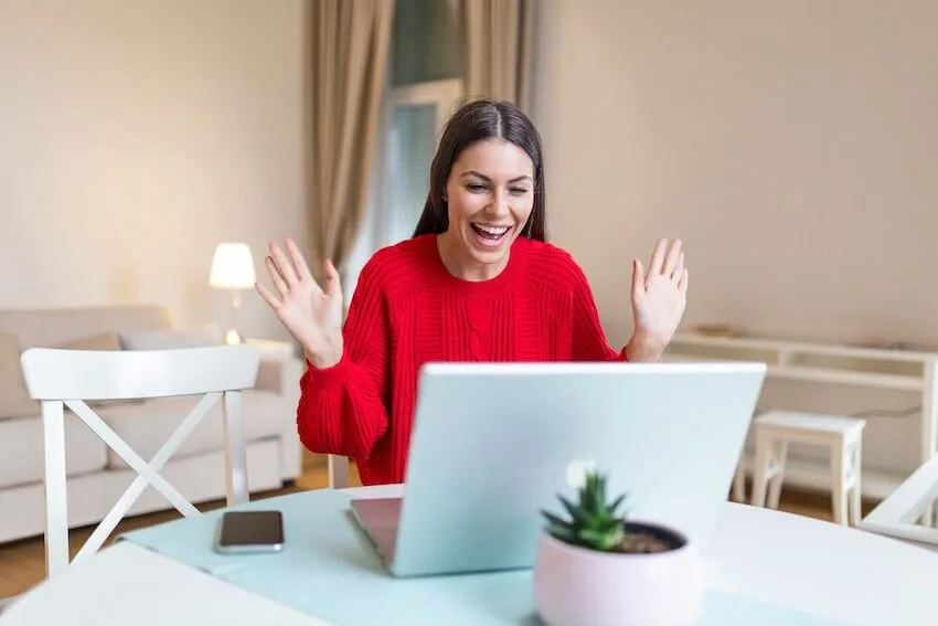 woman in a red sweater with her arms raised in celebration