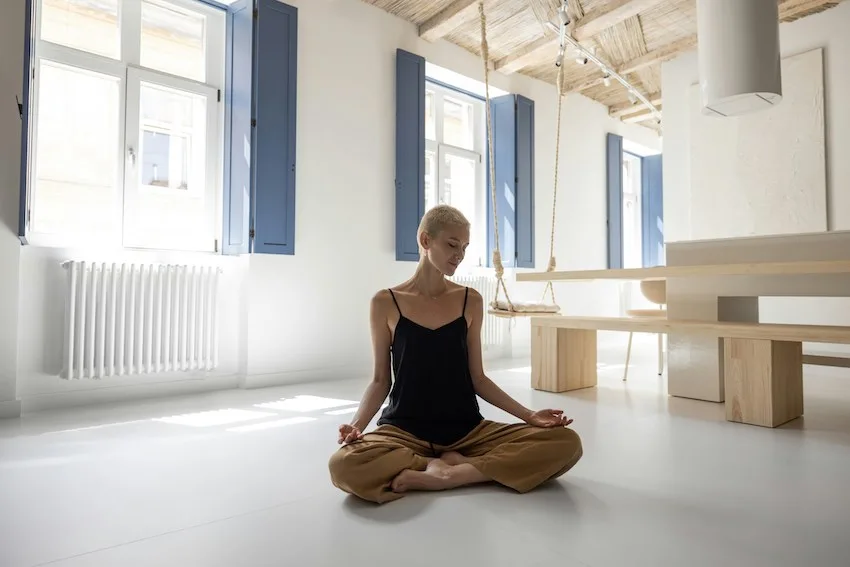 woman in black camisole meditating in a minimalist space