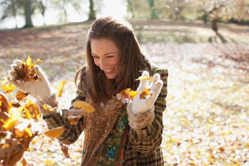 woman playing with autumn leaves