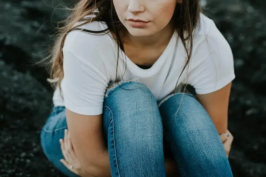woman pondering while hugging her legs