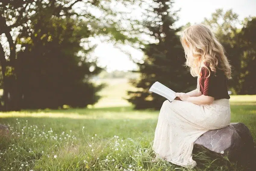 woman sitting on a rock and reading outside