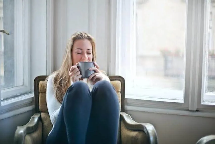 a woman sitting in her armchair enjoying a mug of tea