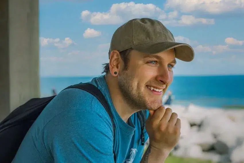 smiling man looking off to the distance with his right hand under his chin