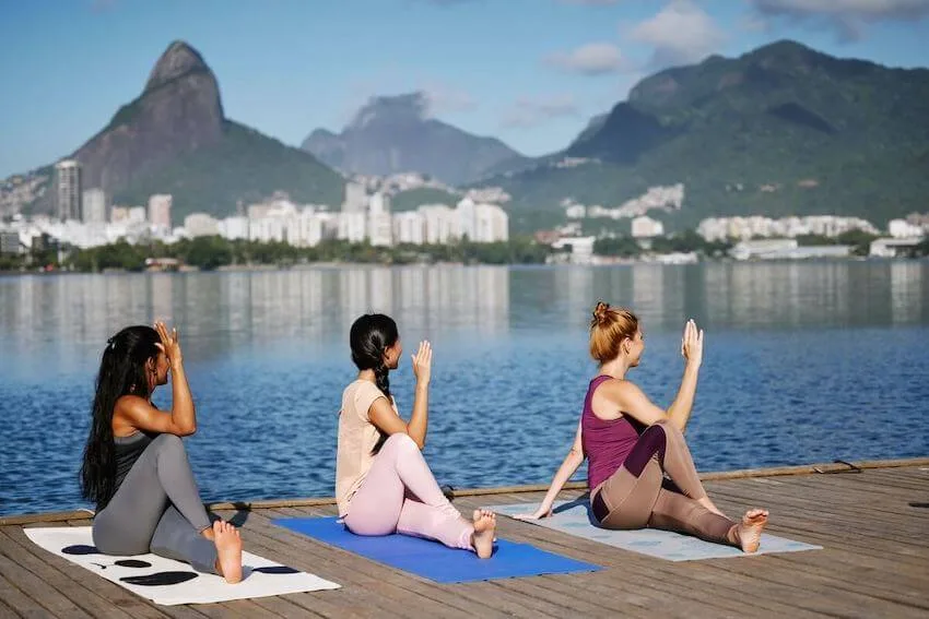 3 women doing yoga at the edge of a boardwalk